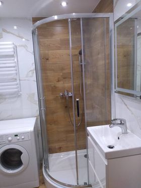 Panele drewnopodbone w kabinie prysznicowej, ściany płytki białe marmurowe - łazienka
