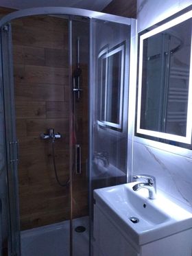 Panele drewnopodbone w kabinie prysznicowej, ściany płytki białe marmurowe - łazienka