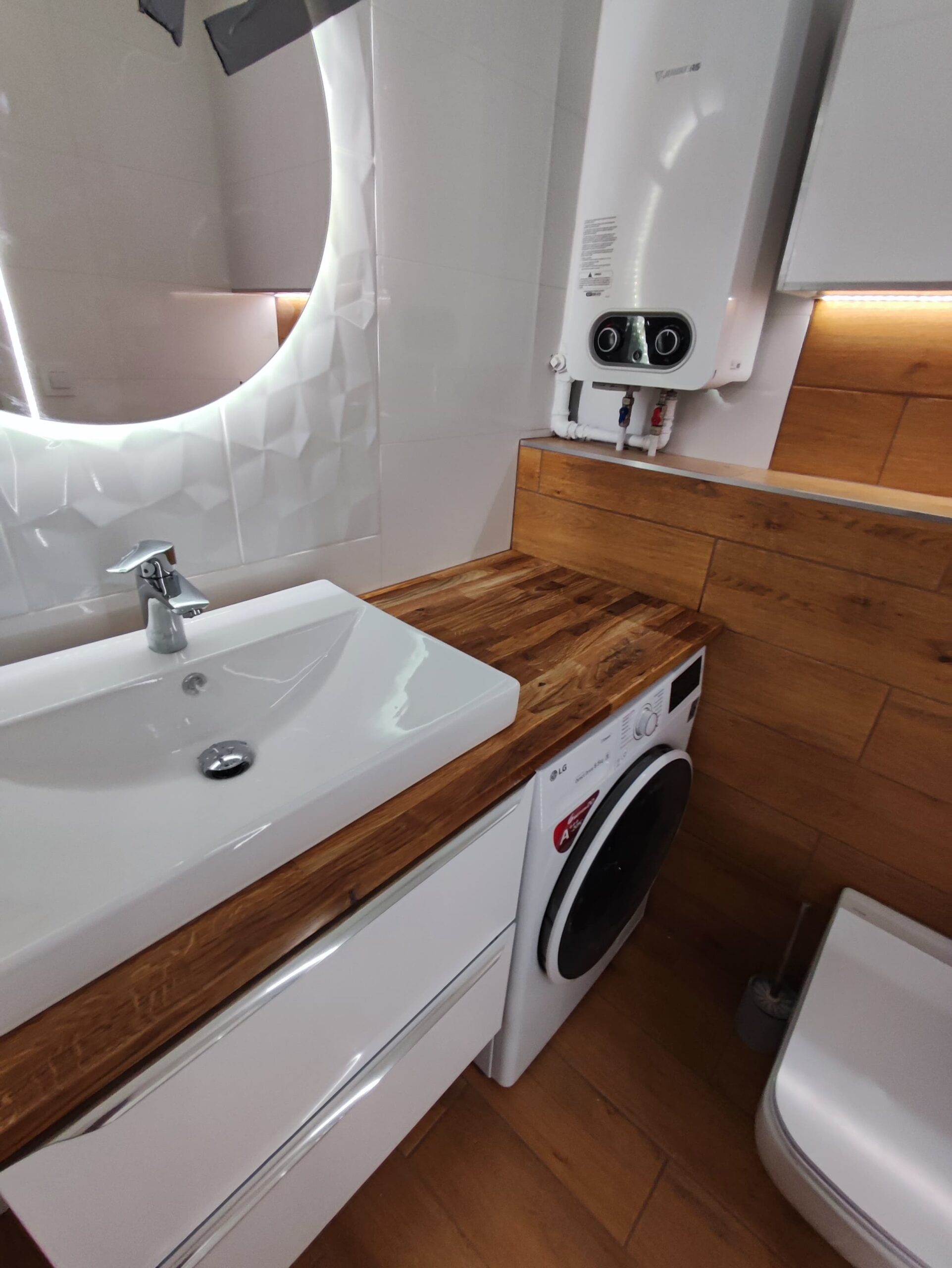Białe płytki oraz panele drewnopodobne - remont łazienki